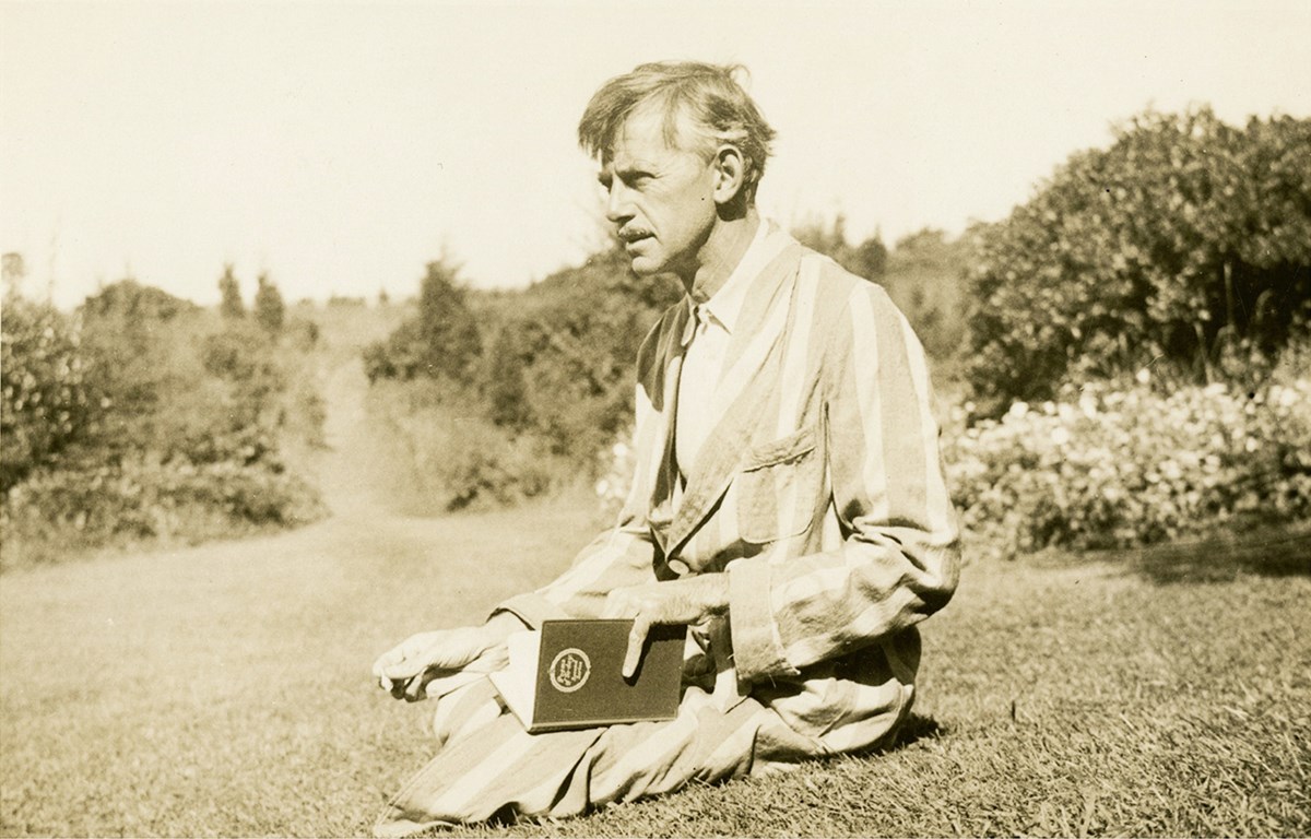Eugene O'Neill sitting in the grass, holding a book.
