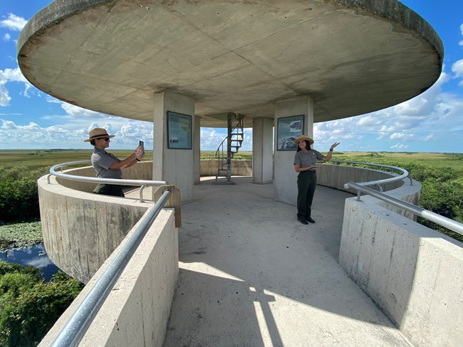 2 rangers standing on a cement structure overlooking a grassy area