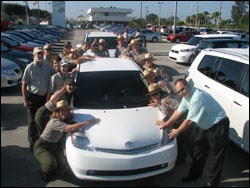 a photo that shows several park employees hugging their new hybrid car
