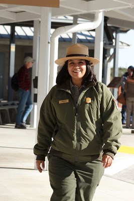A smiling park ranger, walking towards the camera