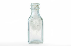 Aged clear glass medicine bottle with markings imprinted below the neck.