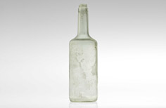Bottom of aged clear glass bottle with imprinted markings.