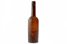 Aged brown whiskey bottle with stamped horseshoe and wording.