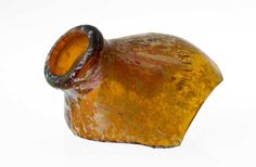 Aged amber glass top of a bottle fragment with embossed words.
