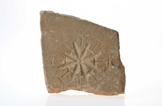 Piece of stone with dial pattern indented on it.