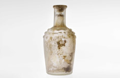 Aged clear glass perfume bottle with dappled ridges below the neck.
