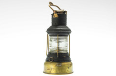 Glass lantern with metal base and fixtures, used for navigating boats.