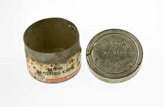 Aged metal container with lid and torn label.
