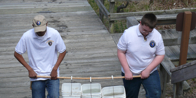 Volunteers carry water buckets up stairs to fill fish tanks