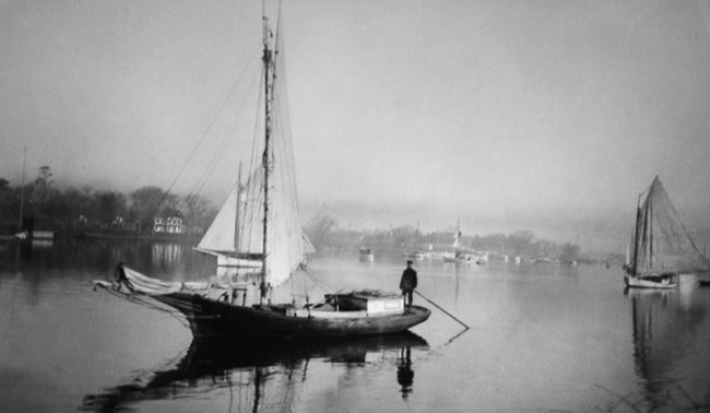A black and white image of a Gil Smith boat floats on the Patchogue River.