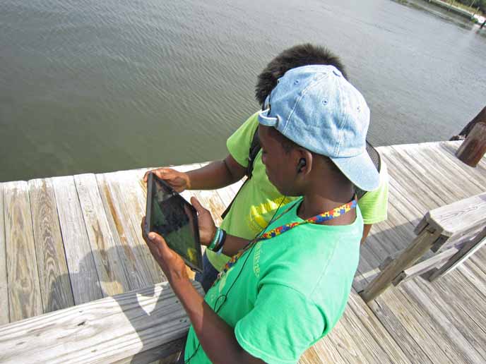 Children watch a park video on an iPad.