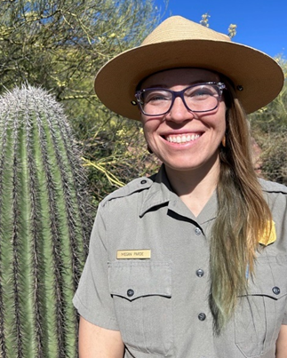 Head and shoulders photograph of Megan Parde wearing a full park uniform and flat hat with a cactus to her right hand side