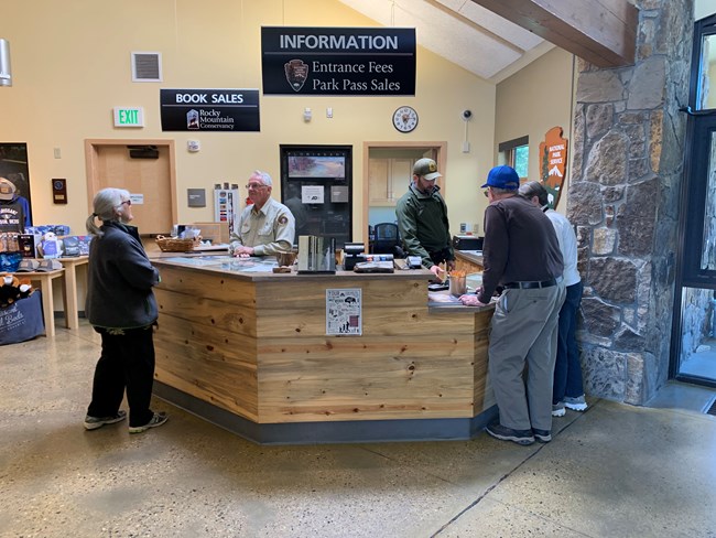 Visitors gather at a wooden information desk to ask Park staff questions.