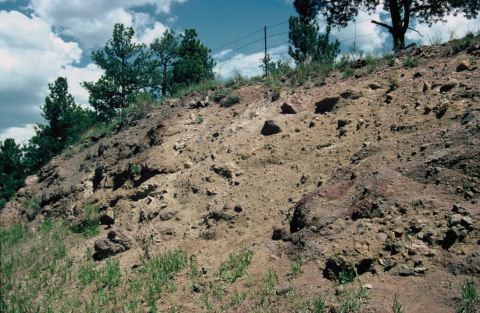 Roadcut featuring rocks ranging in size from large boulders to pebbles under hillside