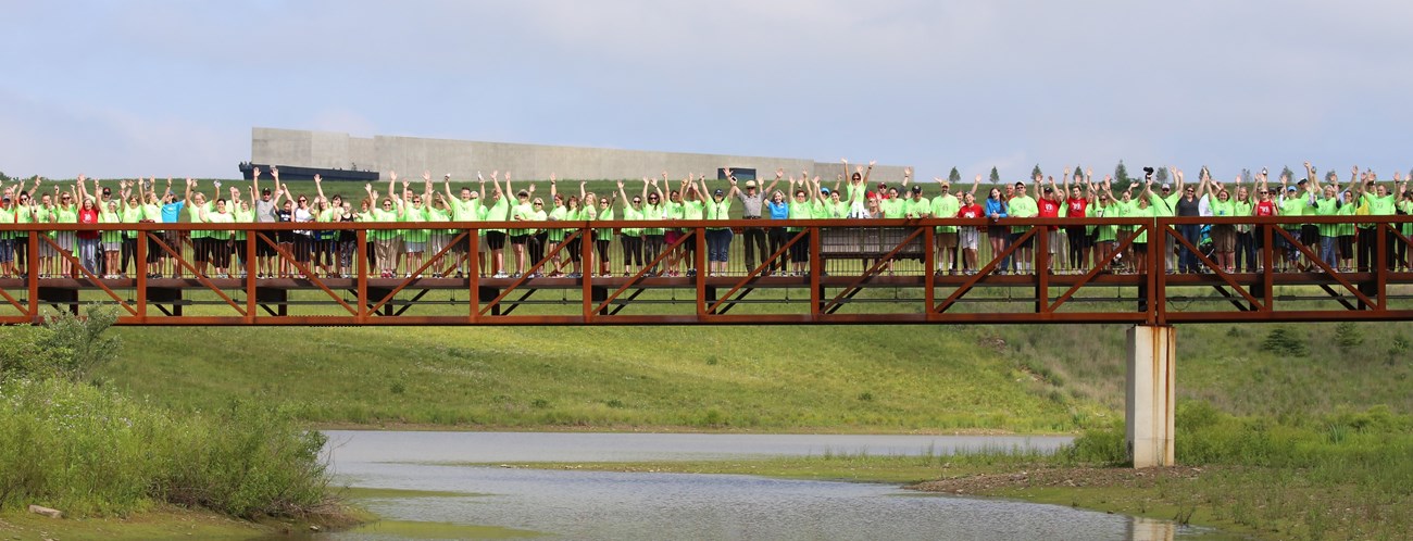 A group of visitors waving from the wetlands bridge