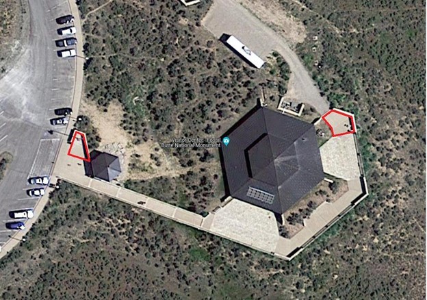 An aerial photo of a building and parking lot. An area to the top right of the building and an area near the parking lot are circled red.