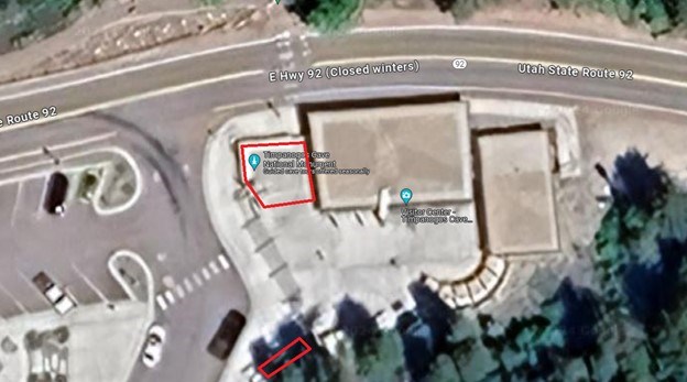 Aerial photo of a building and parking lot. An area to the left of the building and down to the left in a concrete area are circled in red.