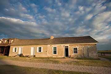 A house featuring a large roof and a small porch, set against a clear sky.