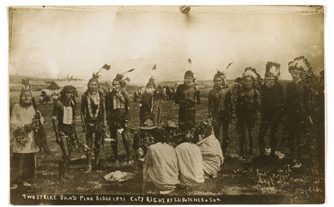 Historical image of Native Americans standing around a fire.
