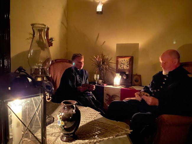 Man and woman in period clothing playing cards.