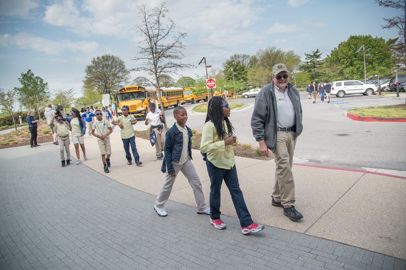 Park volunteer walking students from bus to Visitor Center