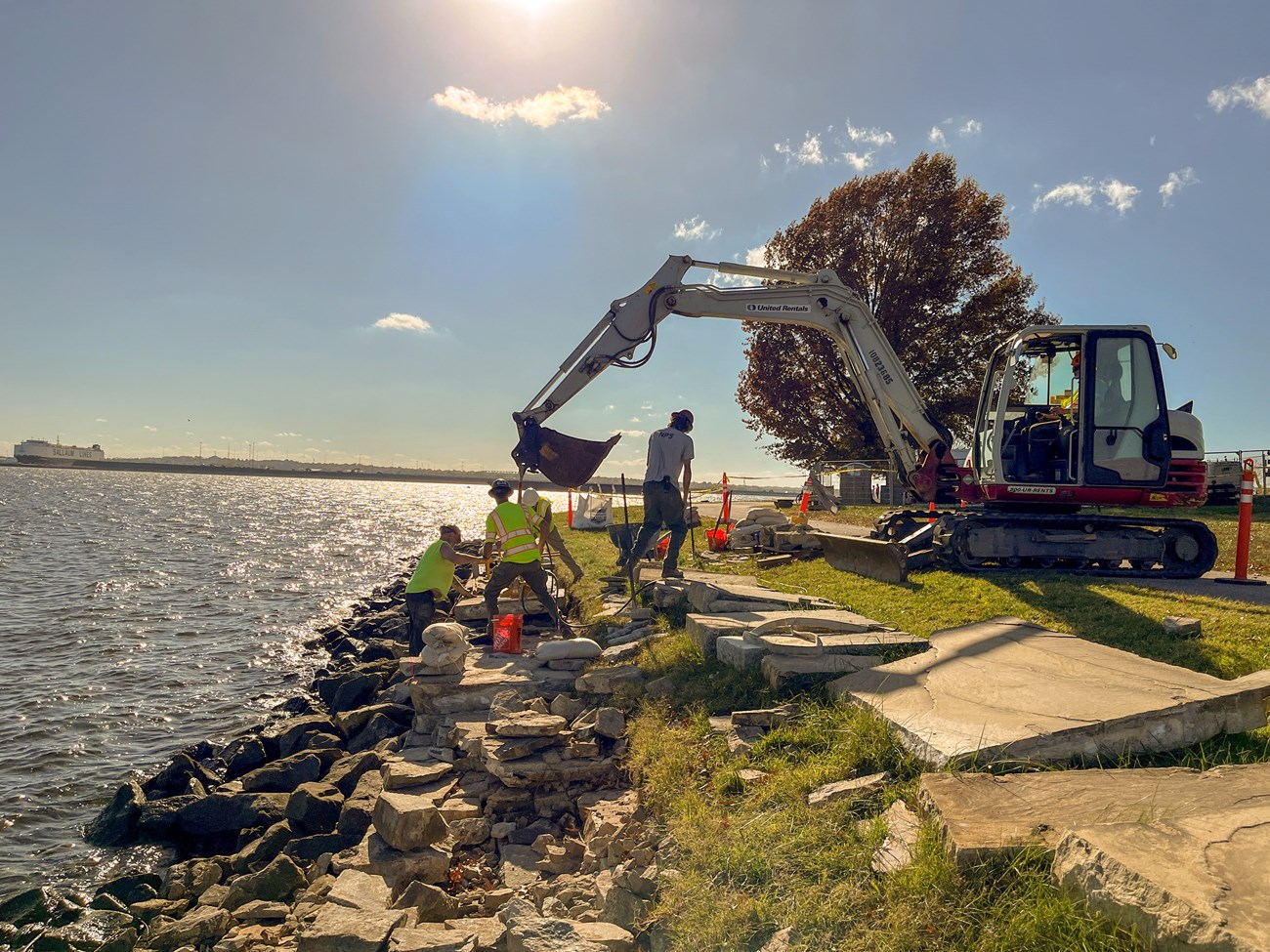 Preservationists using equipment to move and reset granite seawall capstones