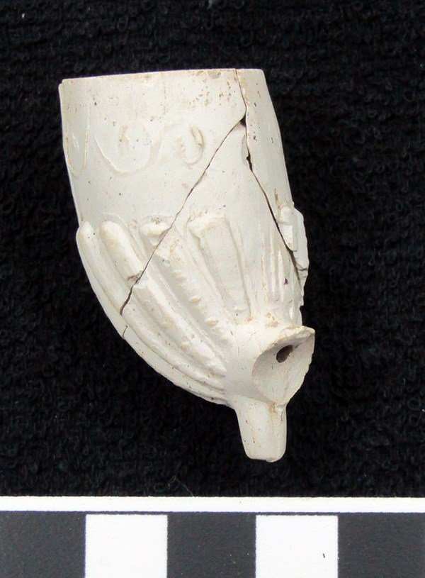 white ceramic fragments that were put back together into a whole pipe bowl. A linear decoration is present on the bottom half.