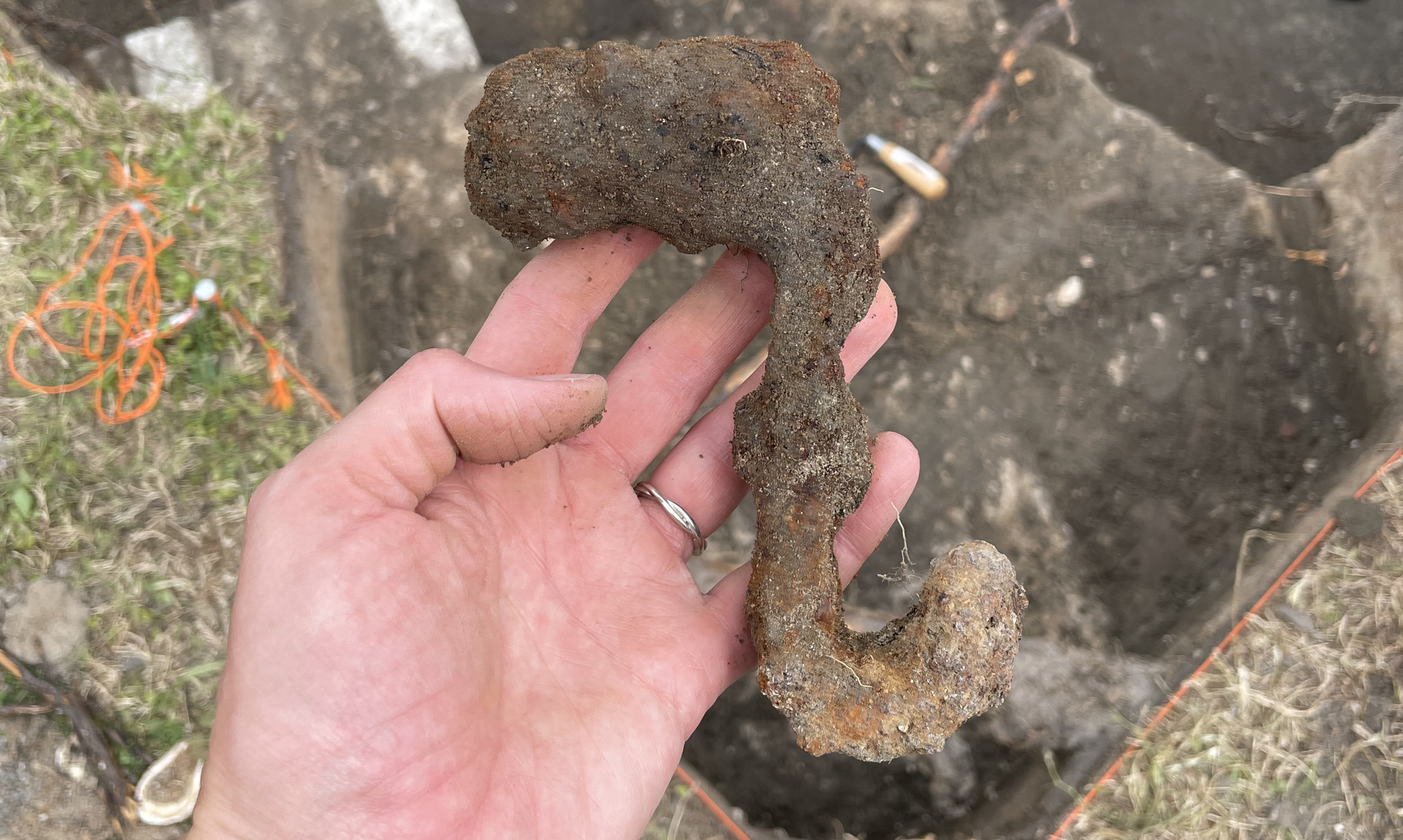 thick, heavy rusted iron hook in an archeologist's hand