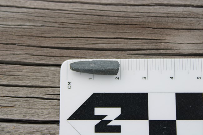 Inch-long fragment of slate shaped like the pointed end of a pencil.