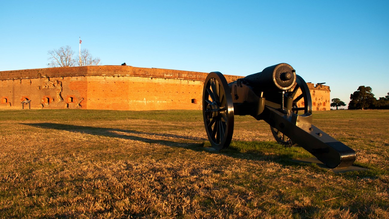 A black cannon points at the brick walls of the fort.