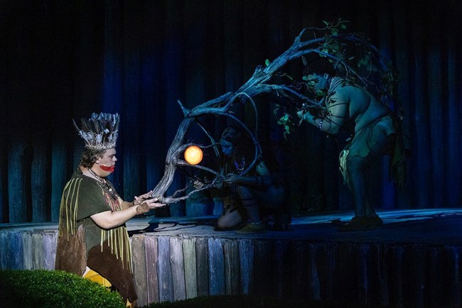 Native man interacting with a bear puppet