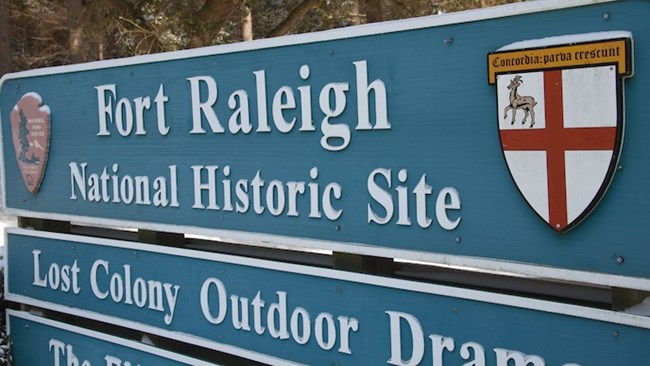 Snow dusts the parking entrance sign. It reads, "Fort Raleigh National Historic Site."