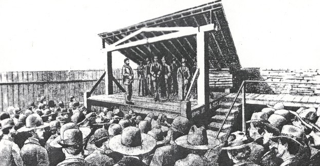 drawing of execution of Cherokee Bill showing large crowd gathered around gallows structure.  Cherokee Bill is standing on scaffold with a rope hanging from the cross beam.  Standing in the distance on the scaffold is a woman, Cherokee Bill's mother.