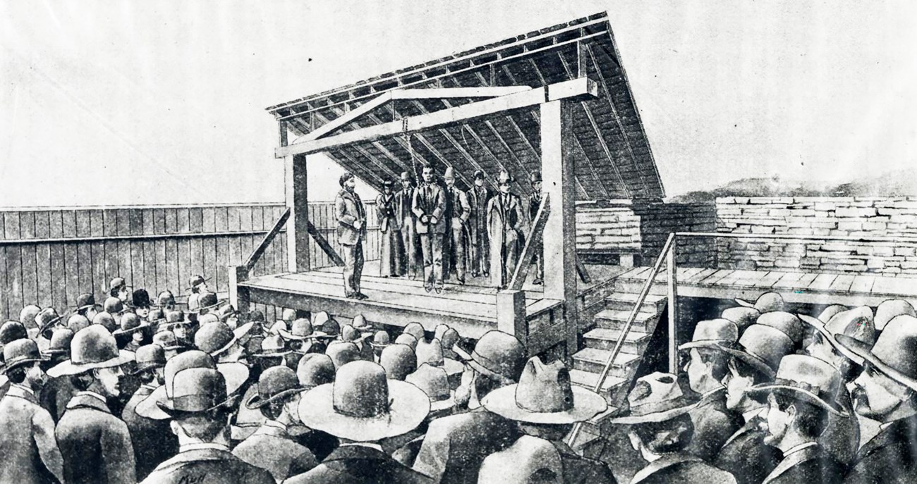 A drawing of Cherokee Bill with a noose around his neck and five other men standing on the gallows at Fort Smith surrounded by a crowd.