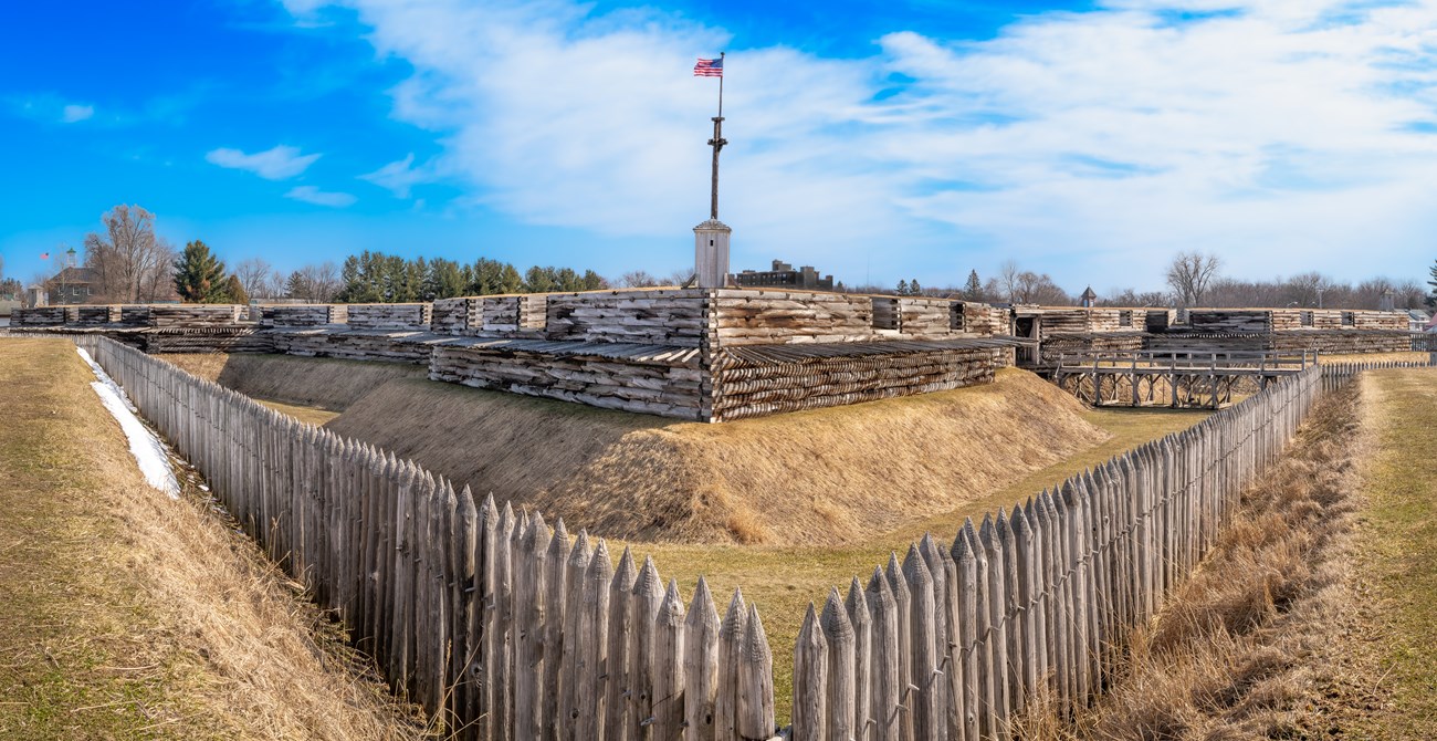 Horizontally in front of you, the wooden flagpole rises from the fort's large walls.