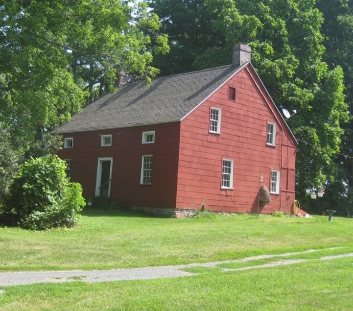 BlogHousePicture1 A small, red clapboard house surrounded by green trees.