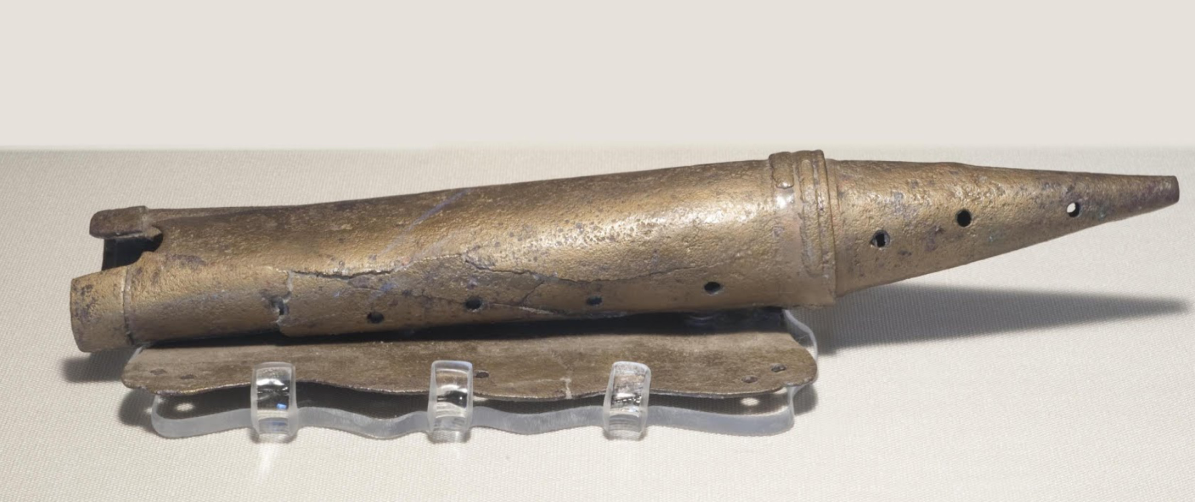 A slightly squished metal tube with holes in it and a pointed end.