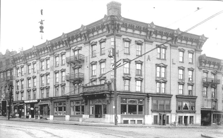 A large brick building that sits on the corner of a city block. About 5 stories tall. Has the words "STANWIX HALL" posted in big lettering.