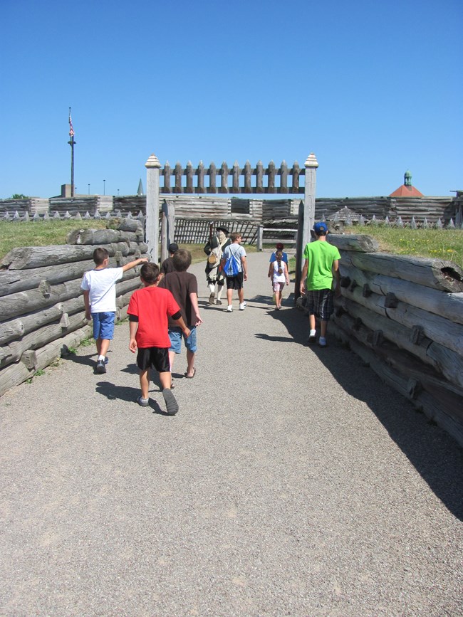 In front of you, several little children run through the fort's picket gate. A continental soldier walks with them.