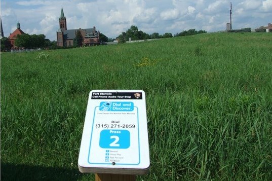 a blue and white sign in front of a green grassy field