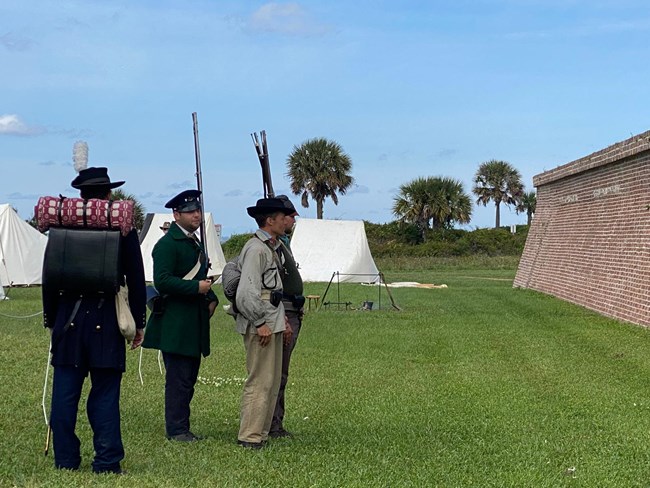 A group of living historians face the wall of Fort Moultrie