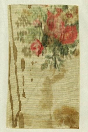 Woven fabric swatch with red and green floral pattern and dark red-brown stains