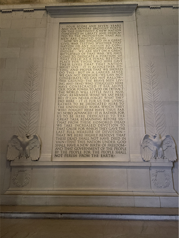 The white marble walls of the Lincoln Memorial's interior. The words of Lincoln's Gettysburg Address are inscribed into the marble. Carved eagles face each other at the bottom of the text.