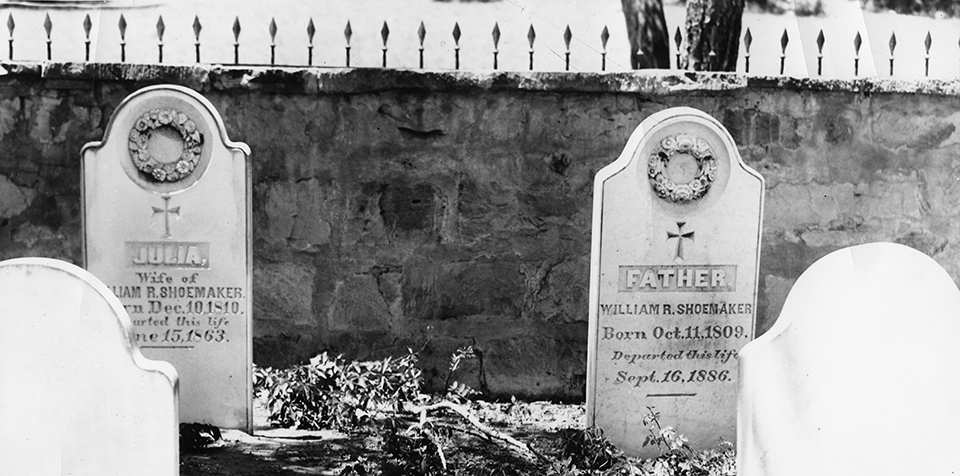 Two headstones, each with a garland and cross