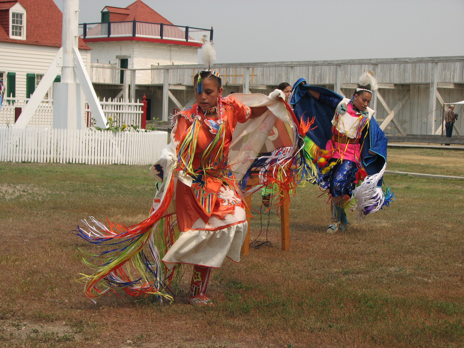 Woman in bright colored dance outfit dances in the courtyard.