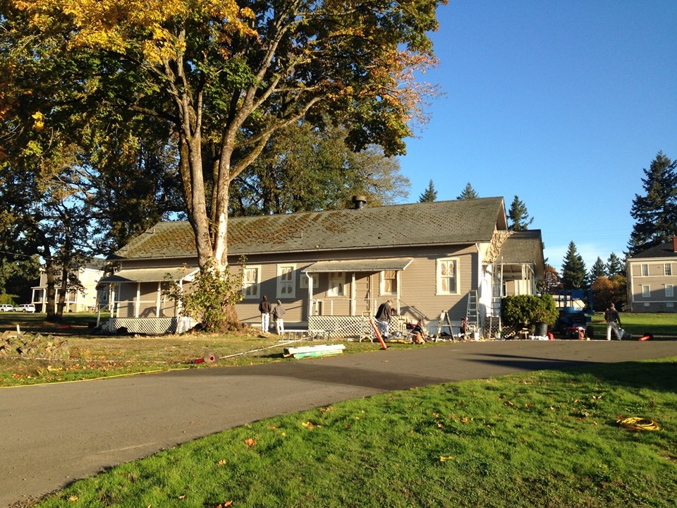 The building from the first photo now has a coat of beige-colored paint and is surrounded by painters.