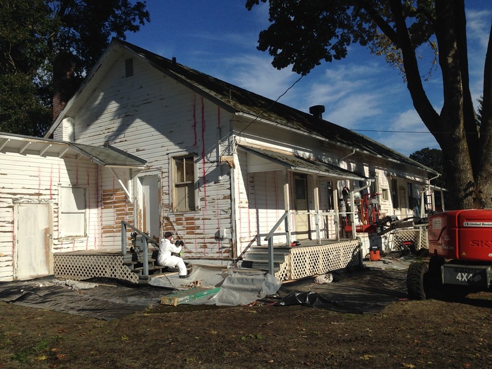 Painters in tyvek suits apply primer to a building