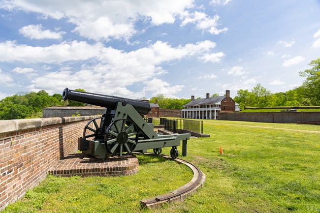 A cannon on a swiveling carriage on the fort wall.