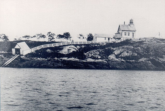 Historic photo of island shoreline with buildings and fence