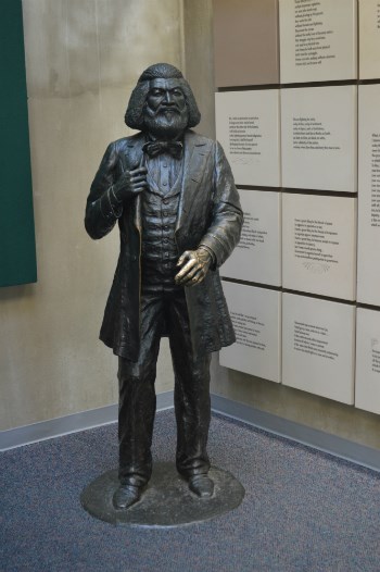 A statue of Frederick Douglass standing next to text panels